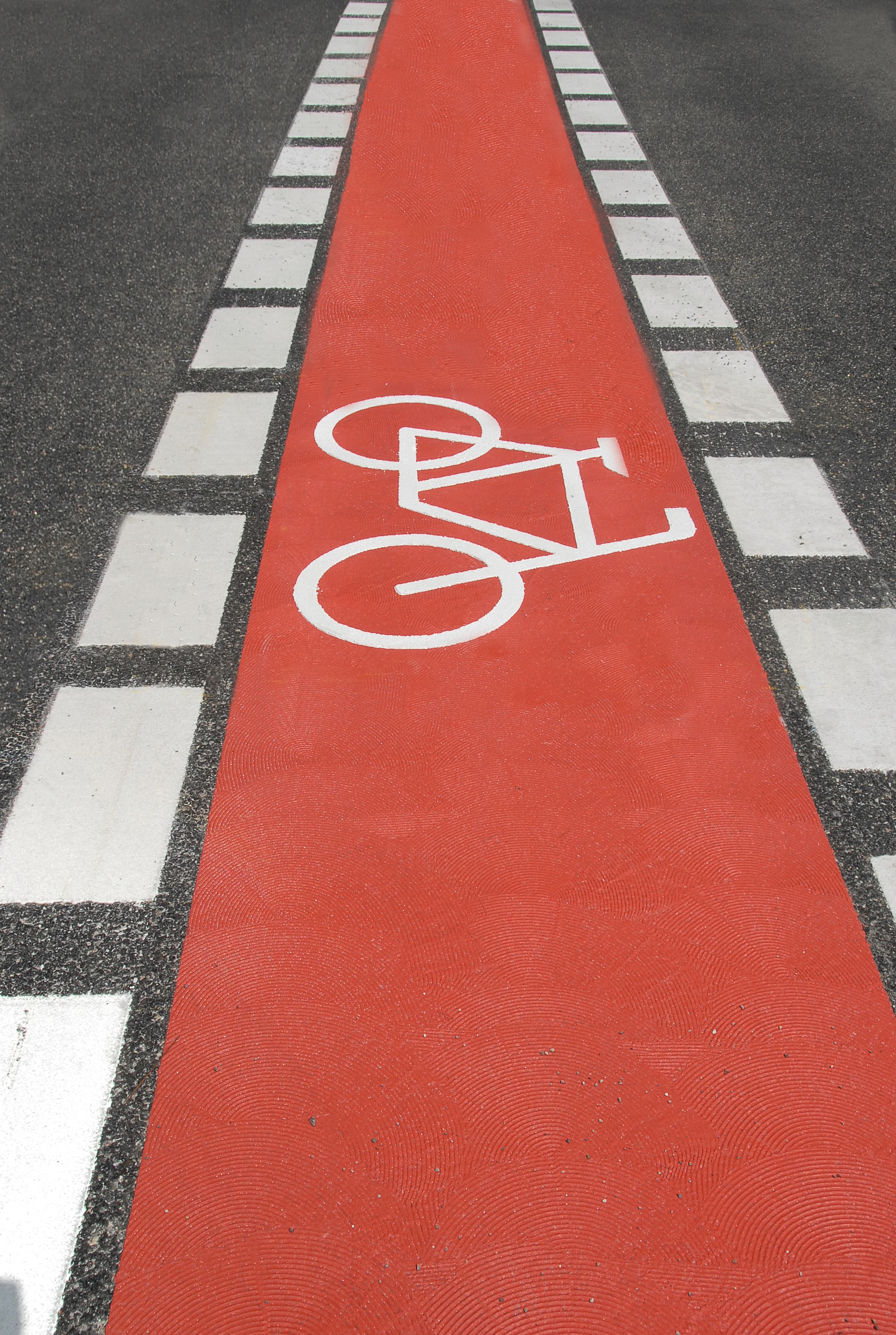 Red bicycle lane marked with a bicycle pictogram made of Triflex cold-applied plastic on an asphalt roadway