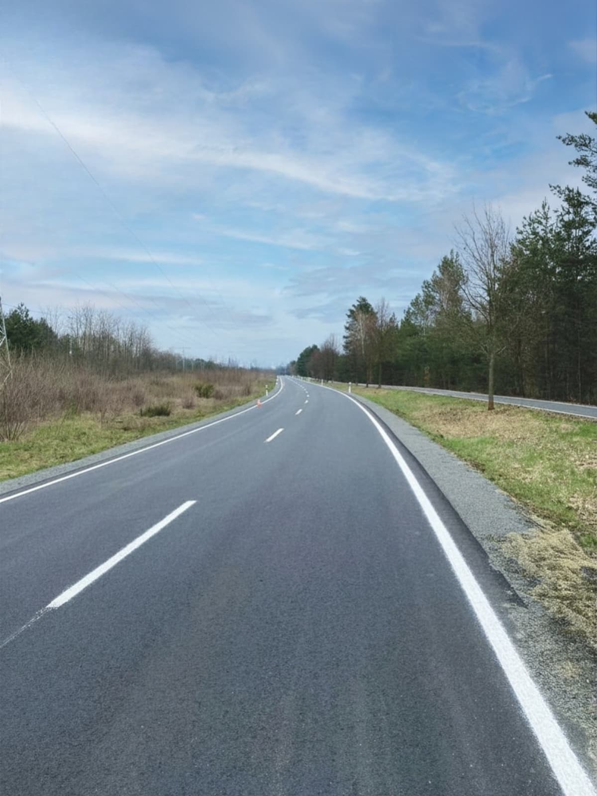 Markierte Landstraße mit Fahrbahnrandmarkierung auf asphaltierter Verkehrsfläche im ländlichen Bereich
