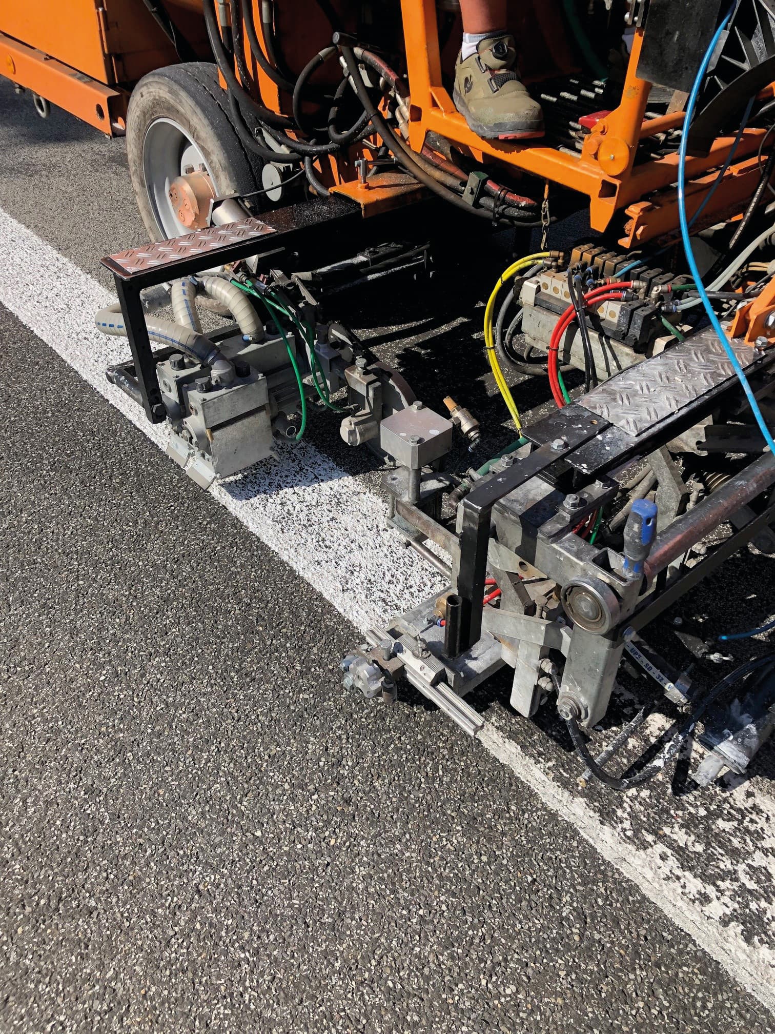 Maschinelle Verarbeitung einer Fahrbahnmarkierung mit Spezialgerät auf Asphalt für präzise und wirtschaftliche Markierungsarbeiten