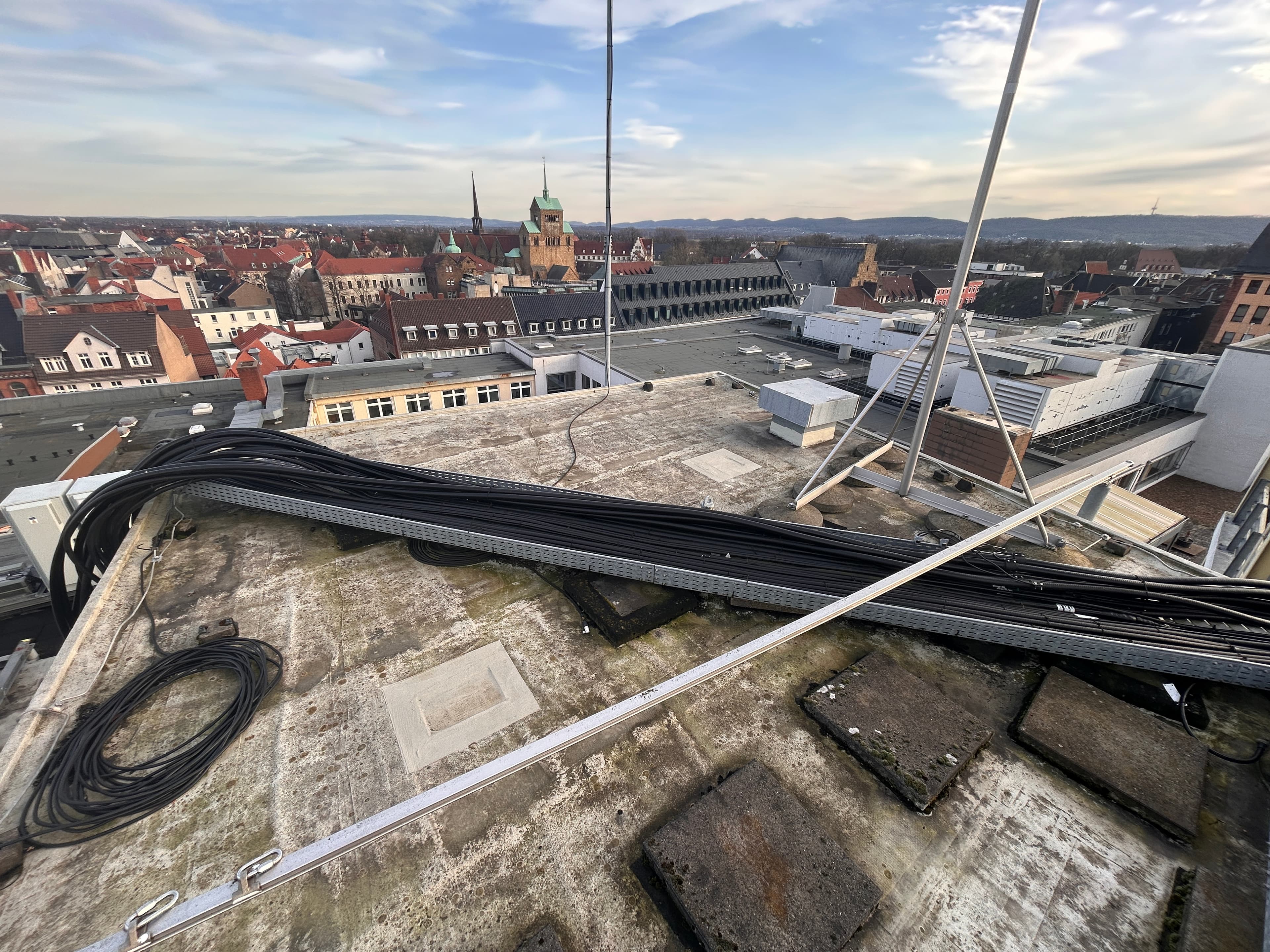 View from the roof of a building in Minden, with visible utility lines and roof trusses in the foreground and the historic downtown area, featuring a church and half-timbered houses, in the background.