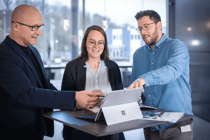 Drei Personen im Beratungsgespräch mit Laptop im Büro