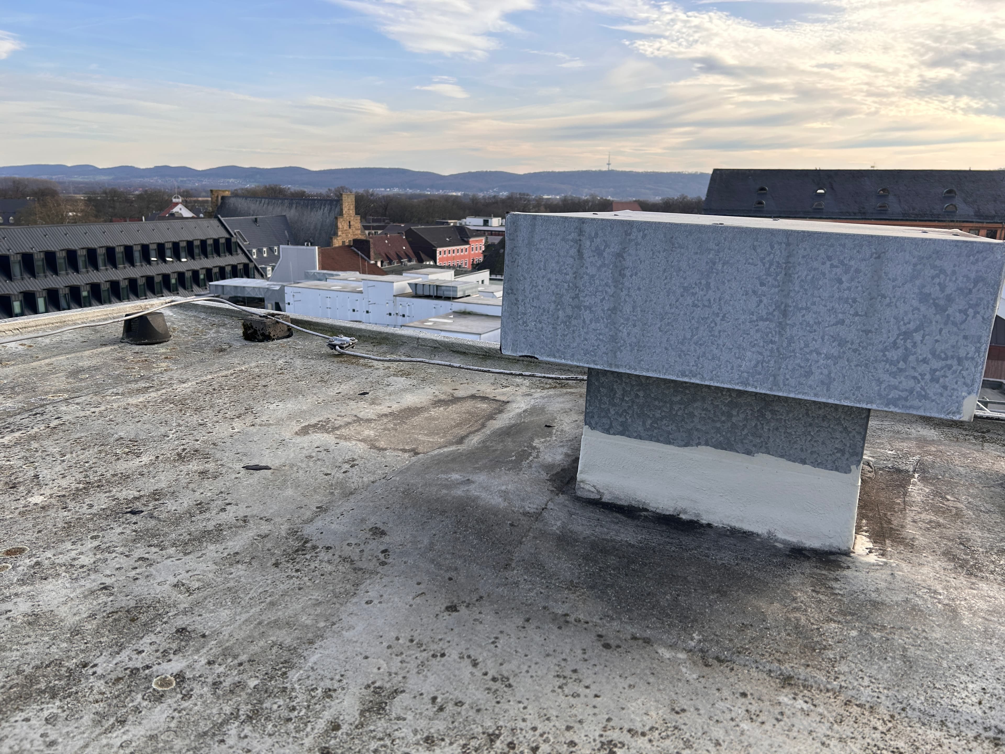 A sealed roof structure with a clad tower on a flat roof in Minden, offering a view of the surrounding buildings and the rolling countryside.