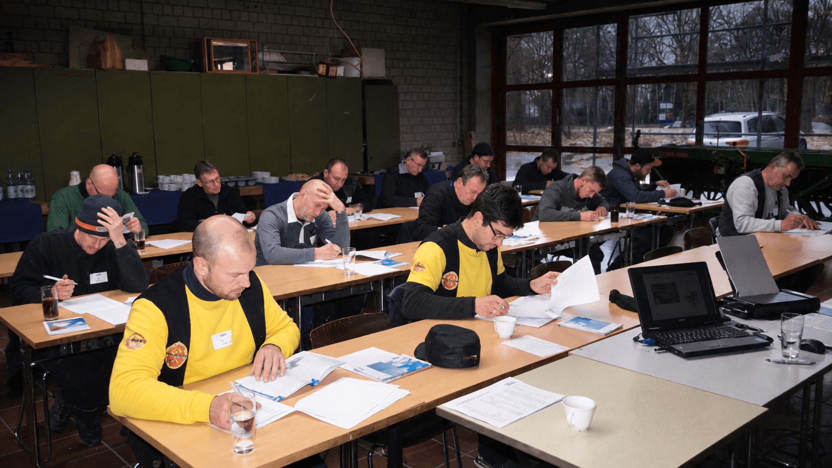 Teilnehmer sitzen im Praxisseminar an Tischen und folgen dem theoretischen Teil zur Verarbeitung von Triflex Abdichtungs- und Beschichtungssystemen.