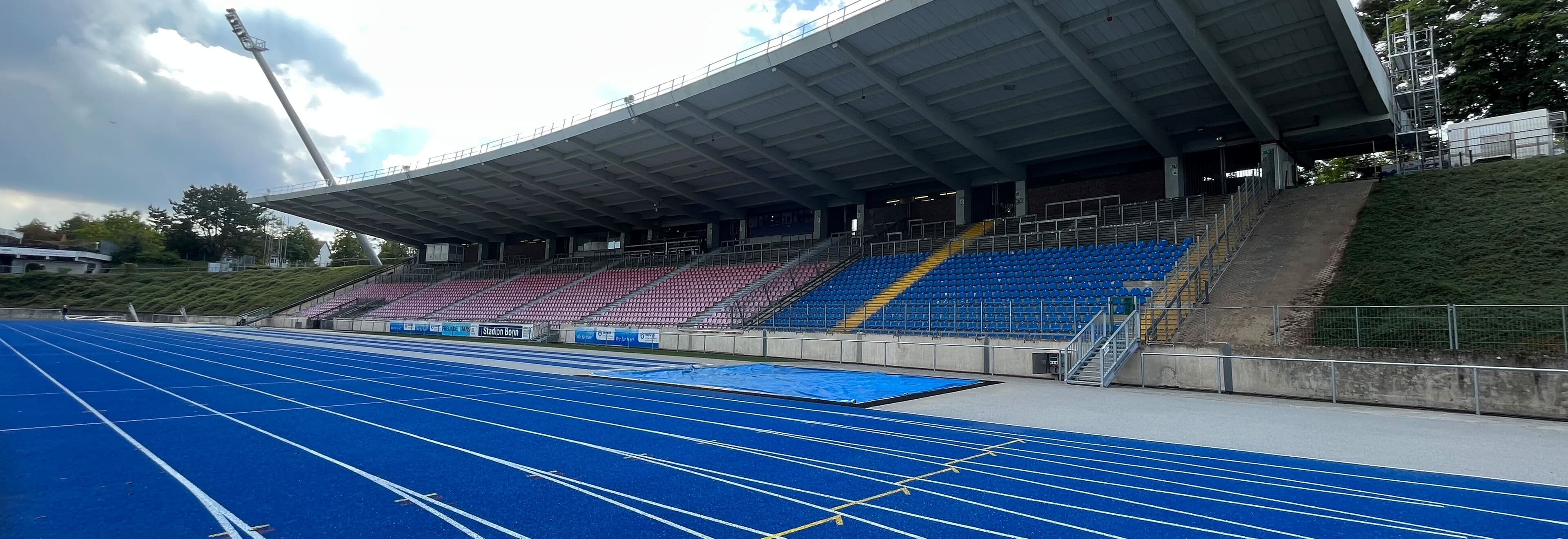 Leichtathletikstadion mit blauer Laufbahn und überdachter Tribüne aus moderner Stadionarchitektur