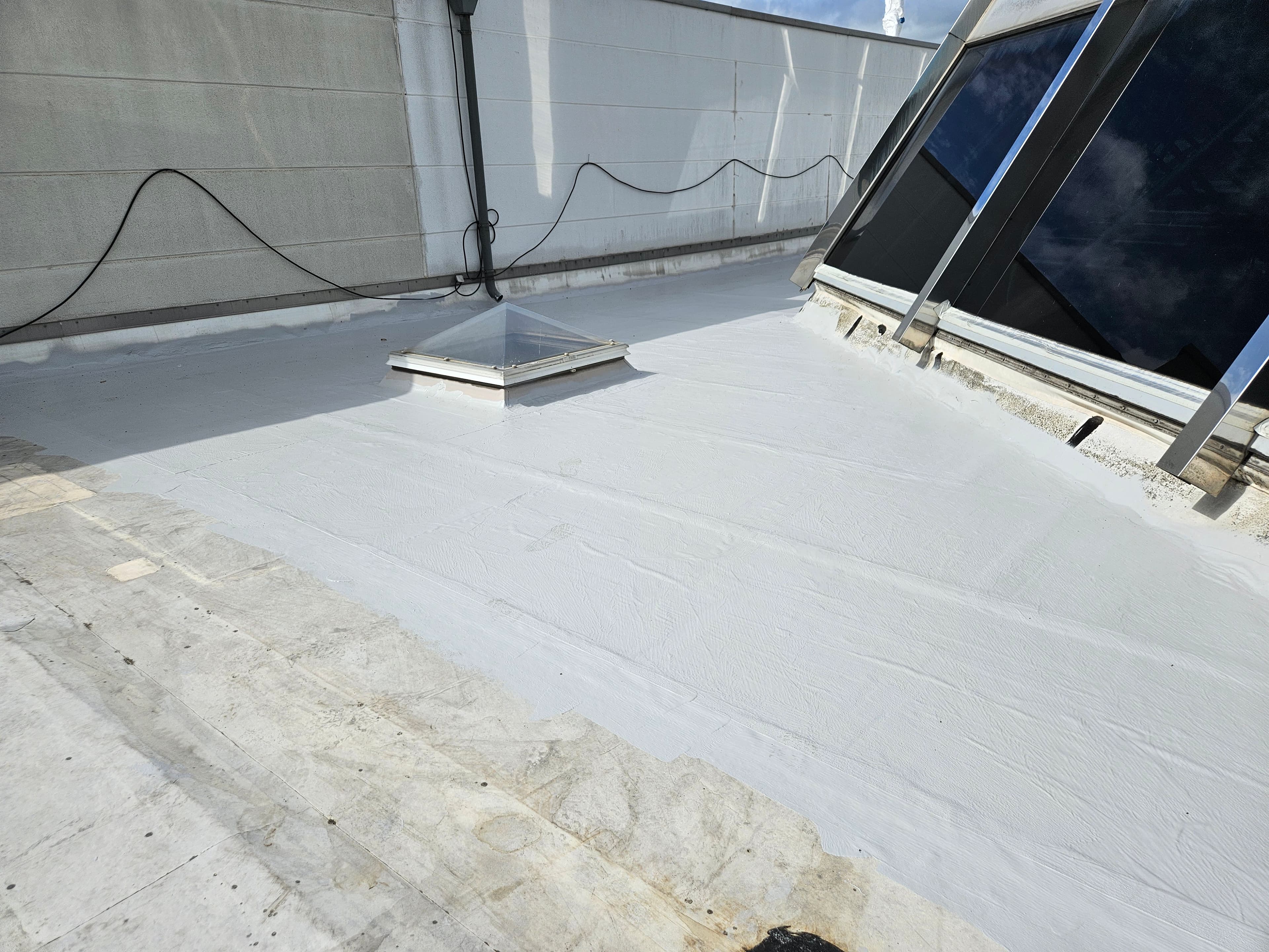 Waterproofed roof surface with a liquid-applied waterproofing membrane in the area of a skylight connection.
