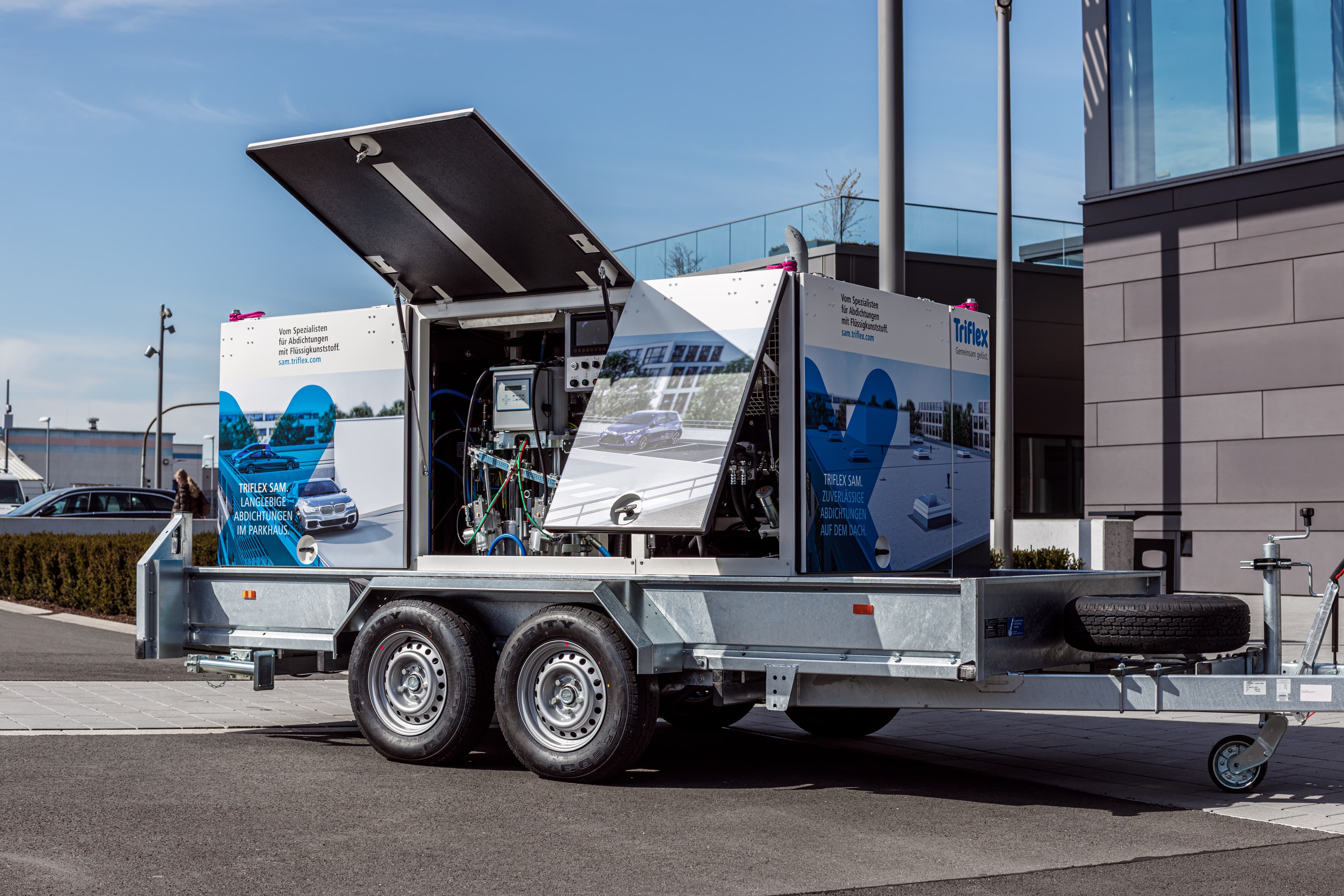 Mobiler Verarbeitungsanhänger mit Misch‑ und Fördertechnik für flüssig aufgetragene Abdichtungen auf einer Baustelle.