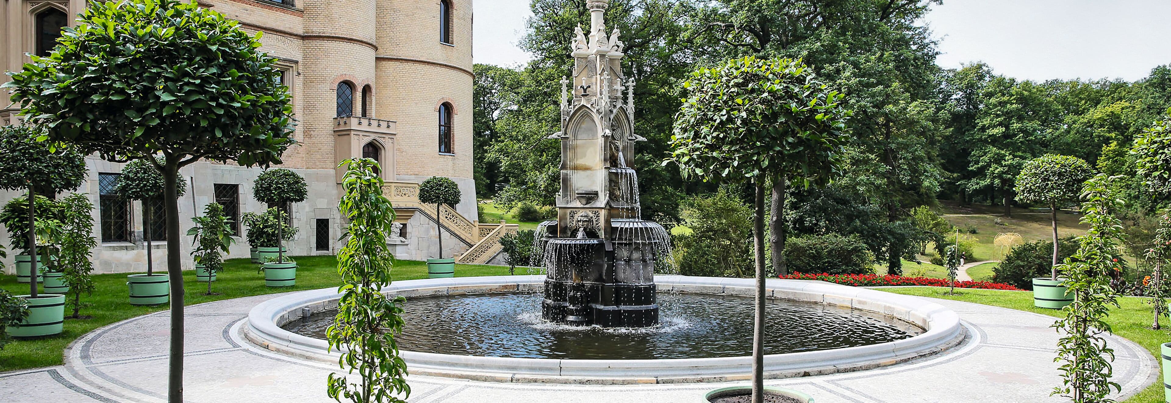 Historic fountain with a water basin in front of the castle complex—an example of waterproofing and restoration of fountains and hydraulic structures