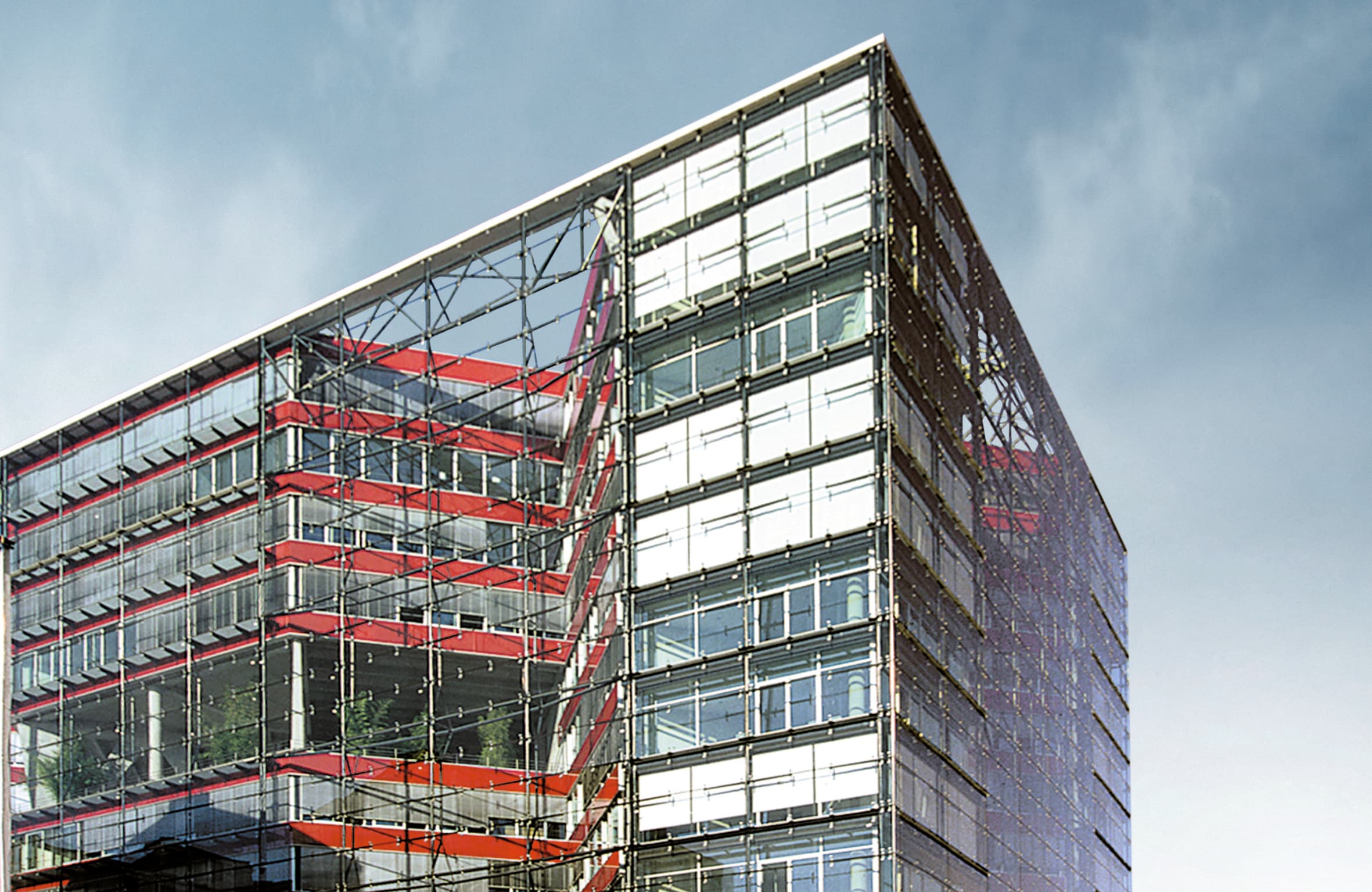 Moderne Gebäudefassade aus Glas und Stahl mit roten konstruktiven Elementen im urbanen Umfeld