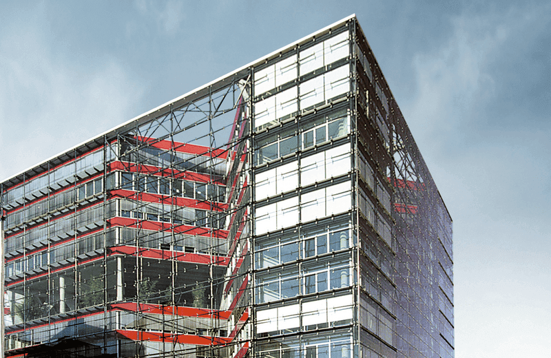 Moderne Gebäudefassade aus Glas und Stahl mit roten konstruktiven Elementen im urbanen Umfeld