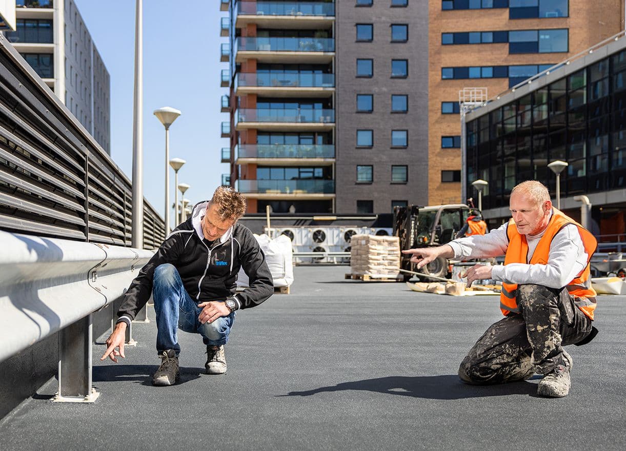 Two skilled workers are inspecting the surface of a coated parking deck as part of the Erasmusbrug project