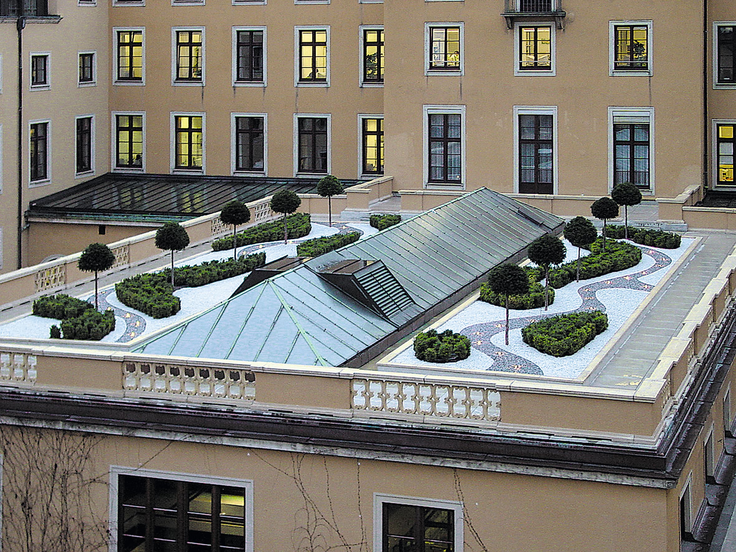 A walkable green roof with an integrated rooftop terrace, walkways, and technical structures on an inner-city flat roof.