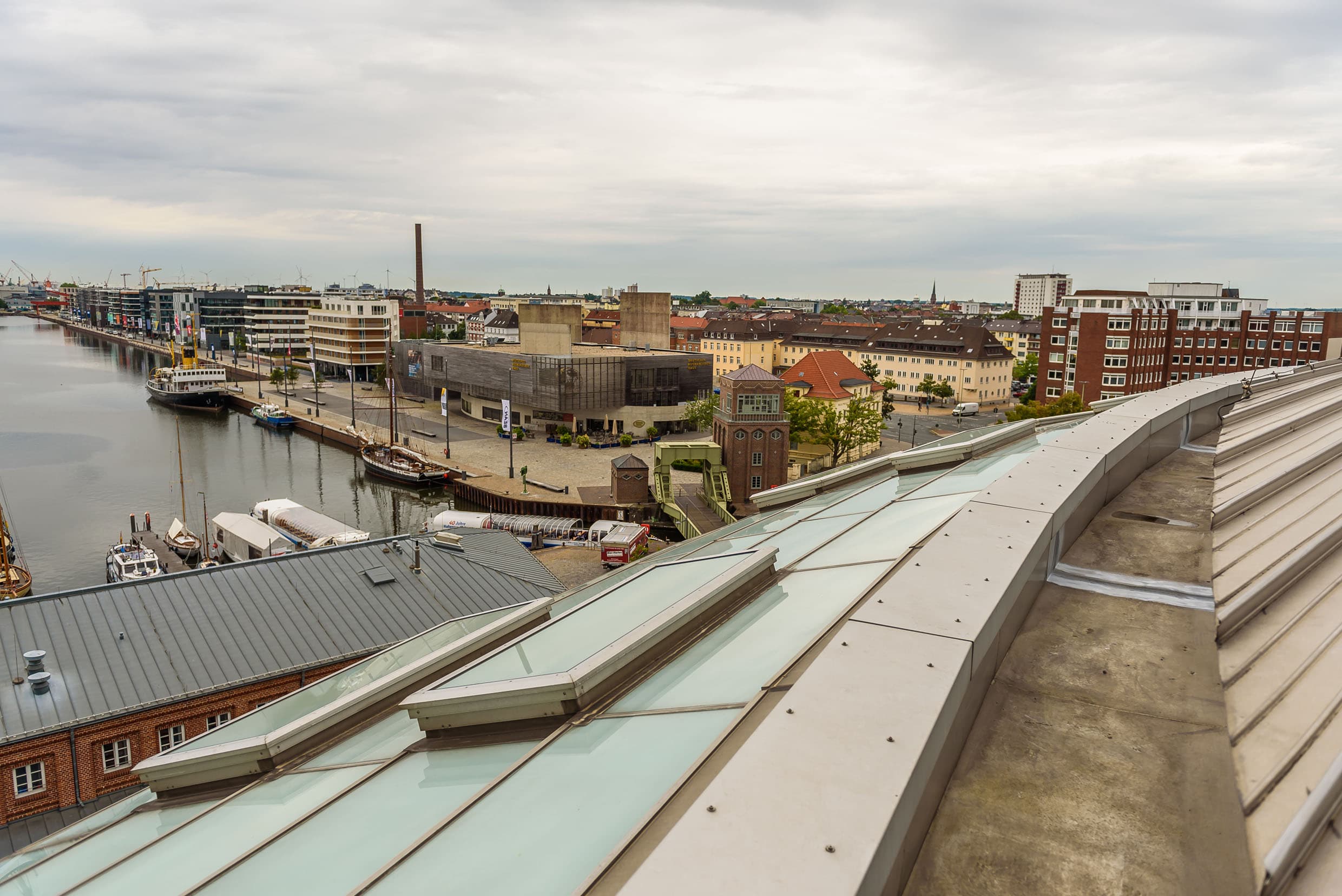 Blick über den Hafenbereich in Bremerhaven mit Wasserbecken, moderner Bebauung und Kaianlagen bei bewölktem Himmel.