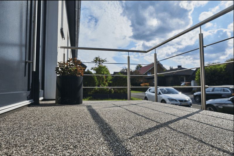 Balkon mit Triflex Stone Design Galaxy Bodenbelag in Natursteinoptik und modernem Edelstahlgeländer bei Tageslicht