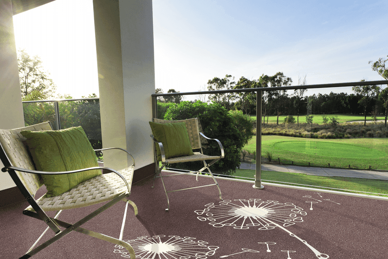 Balkon mit Triflex Floor Tattoo Design „Pusteblume“ auf dekorativ beschichtetem Bodenbelag, zwei Sitzstühle mit grünen Kissen und Blick auf eine Park- bzw. Golfanlage