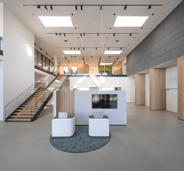 Modern gestalteter Innenraum eines Gewerbegebäudes mit offenem Empfangsbereich, Galerieebene und klarer Architektur