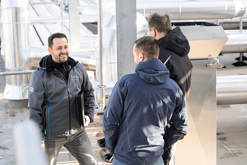 Triflex Berater im Gespräch mit zwei Fachpartnern auf einer Dachfläche