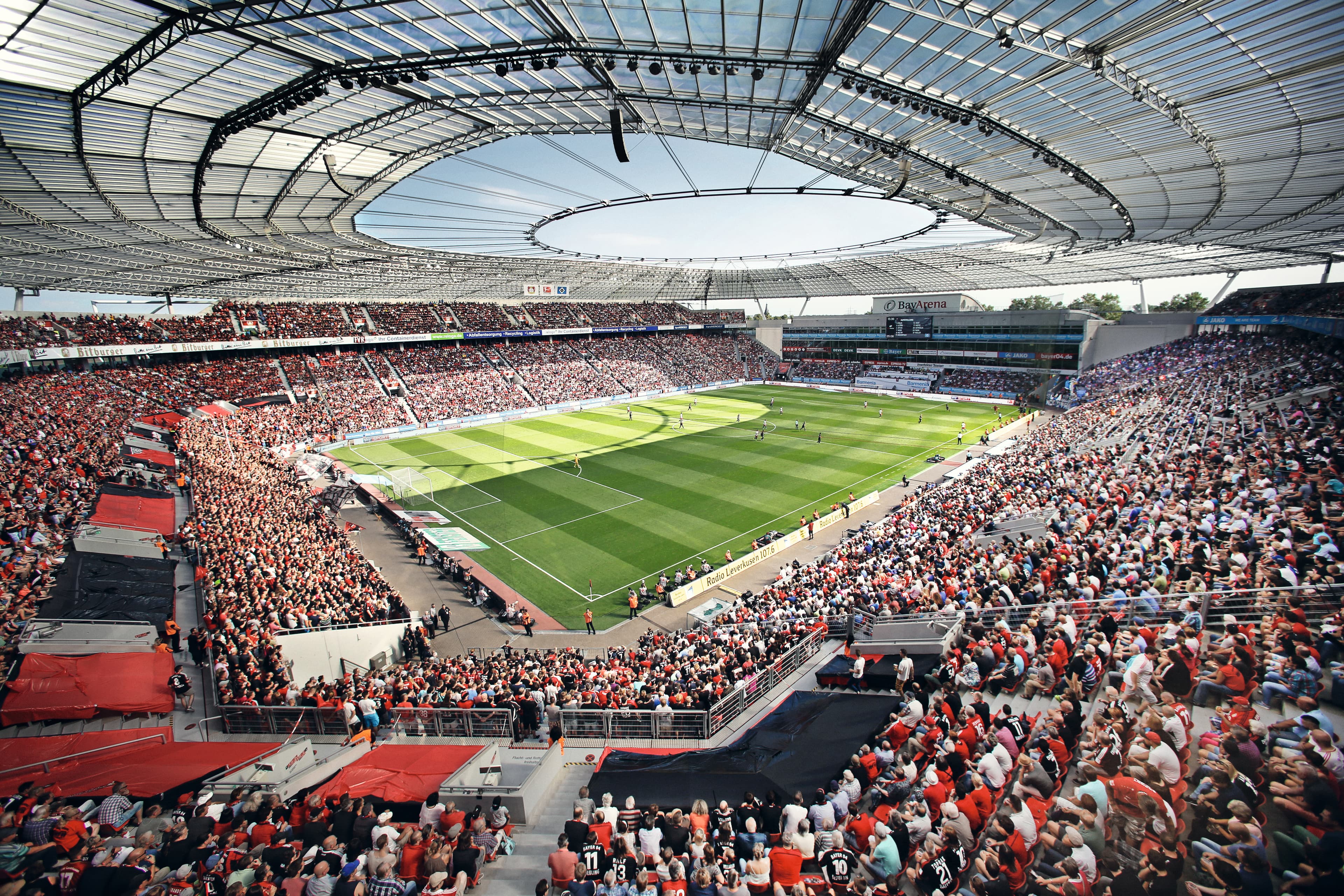 Großes Fußballstadion mit gefüllten Tribünen und überdachtem Spielfeld während einer Veranstaltung.