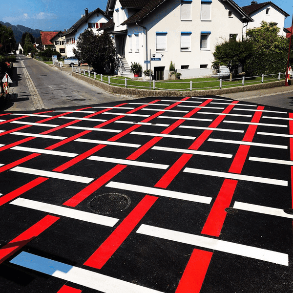 Kontrastreiche Straßenmarkierung in Rot-Weiß mit Karomuster auf dunklem Asphalt – gut sichtbare Verkehrsflächenmarkierung für erhöhte Sicherheit.