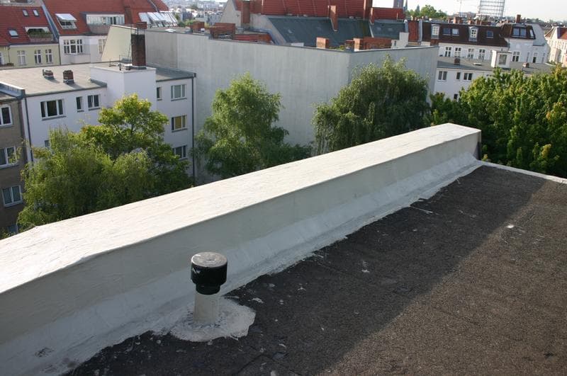 Flachdach eines Wohn- und Geschäftshauses in Berlin nach Sanierung – zuverlässige Dachabdichtung mit Flüssigkunststofflösung von Triflex für komplexe Anschlussdetails.