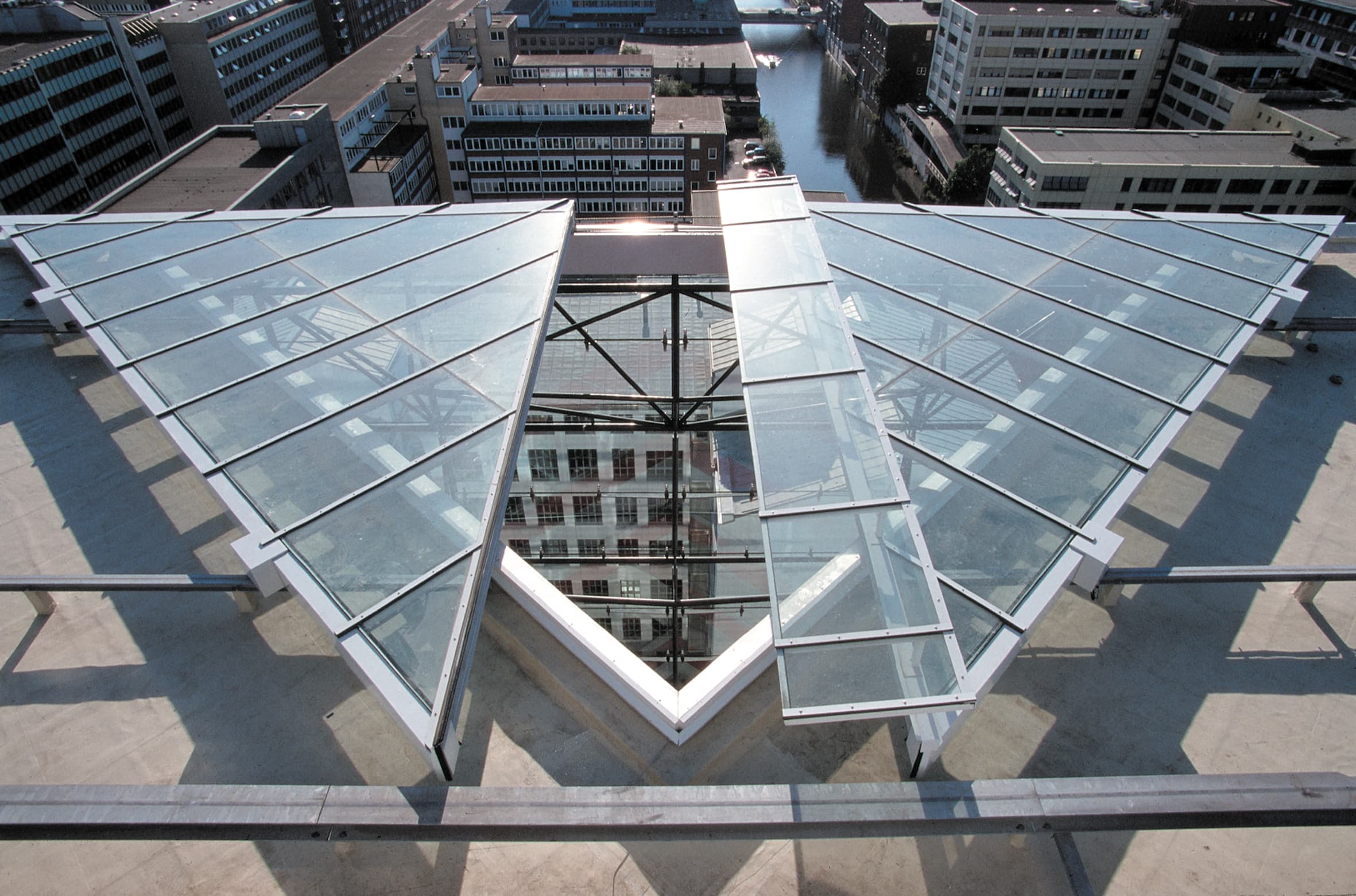 A triangular glass roof structure atop a modern high-rise building, offering a view of an urban office and business district.