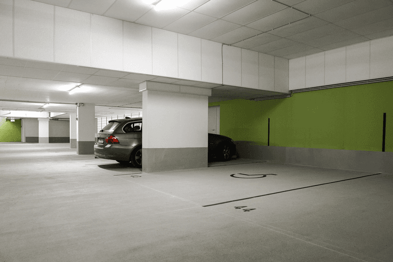 Moderne Tiefgarage mit beschichteter Bodenfläche, Parkplätzen und heller Beleuchtung nach Sanierung.
